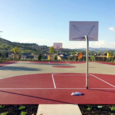 the photo shows a full-size basketball court painted in beige, but all other parts of the basketball court (key, 3-point area, center circle, and surround) painted in red with white striping.