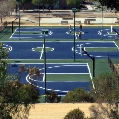 the photo shows three full-size basketball court staggered next to each other and painted in blue courts with green keys, center circle, and surrounds with white striping.
