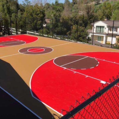 The Photo Shows An Absolutely Gorgeous Full-sized Basketball Court In Adobe Tan, Red In The 3-point Area, Maroon Free Throw Circles, And Red & Maroon In The Center Circle With White Striping Overall