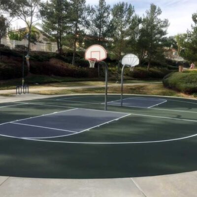 The Photo Shows Two Back-to-back Basketball Courts Repaired And Resurfaced In Green With Gray Keys And White Striping For Paseo Del Sol By Ferandell Tennis Courts.