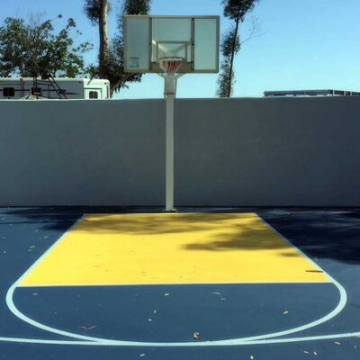 the photos shows a private residential basketball half court in blue and yellow colors with white striping.