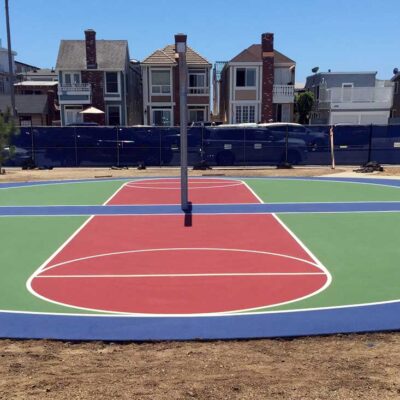 the photo shows a two basketball courts in green with red keys and white striping, back-to-back, on a shared round blue surround.