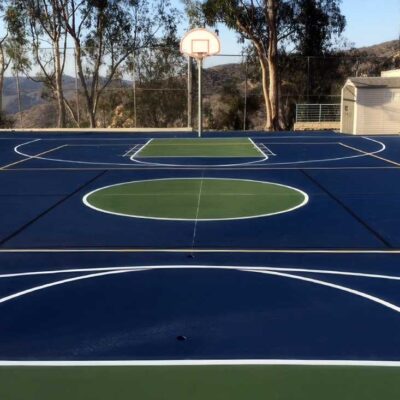 The Photo Shows A Multi-sports And Game Court At Thurston Middle School With A Blue & Green Basketball Court With White Striping, And Overlaid Yellow Volleyball Lines And Overlaid Black Pickleball Lines.