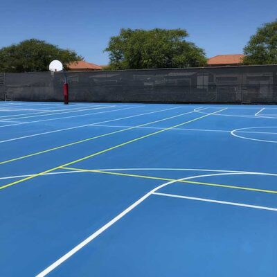 The Photo Shows A Multi-sports & Game Court Built For MCAS Miramar By Ferandell Tennis Courts In Light Blue With White Basketball Court Lines, And Yellow Tennis Court Lines.