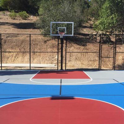the photo shows a bright blue basketball full court with red and grey colored areas with white striping and black pickleball striping.