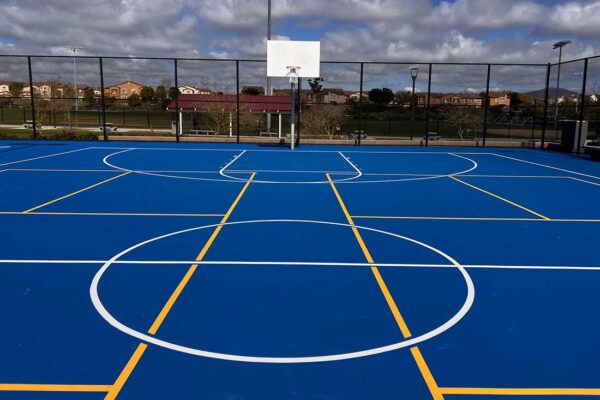 Photo Show A Beautiful Blue Multi-sport Court At Pacific Highlands Ranch Recreation Center With White Striping Of A Full Size Basketball Court Overlaid With Yellow Striping Of Two Pickleball Courts Built By Ferandell Tennis Courts