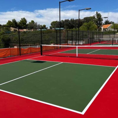 photo shows several medium green pickleball courts bright red kitchen and surround.