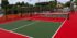 photo shows several medium green pickleball courts bright red kitchen and surround.