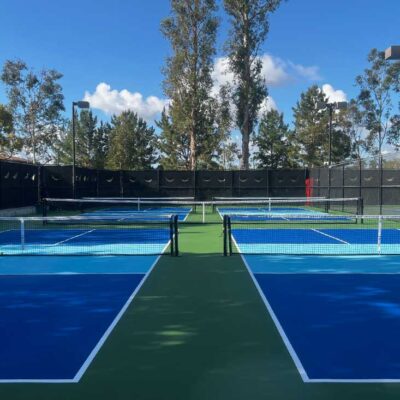 photo shows four pickleball courts built by ferandell tennis courts in irvine, california with blue courts, ice blue kitchens and white striping.