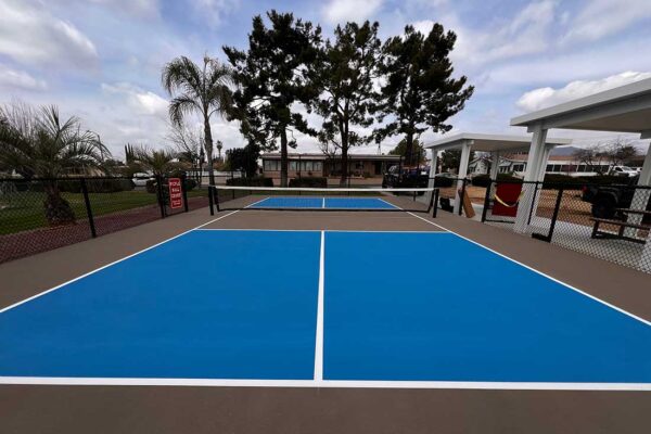 Photo Shows A Pickleball Court At The Plantation On The Lake In Calimesa Using A Fusion Of Light Blue And Ice Blue Sportmaster Colors For The Pickleball Court With White Striping, And A Beautiful Brown Sandstone Surround.
