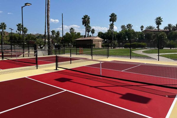 The Photo Shows Several Pickleball Courts Constructed By Ferandell Tennis Courts At The Saboba Reservation In San Jacinto, California Using Custom Colors Of Maroon And Bright Red Courts Surrounded By A Sandstone Surround.