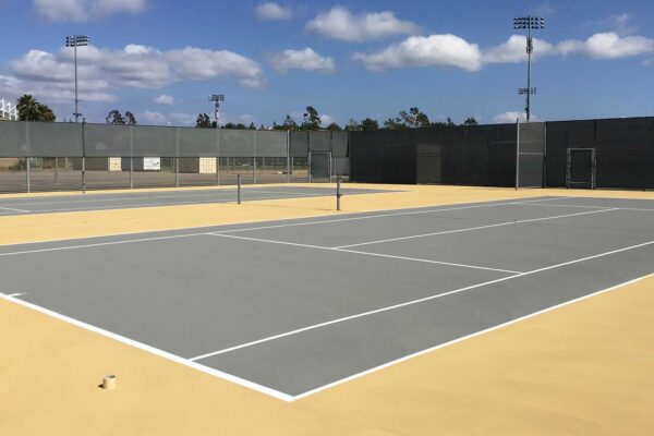 The Photo Shows Two New Tennis Courts Built By Ferandell Tennis Courts In Gray With Sandstone Surrounds.