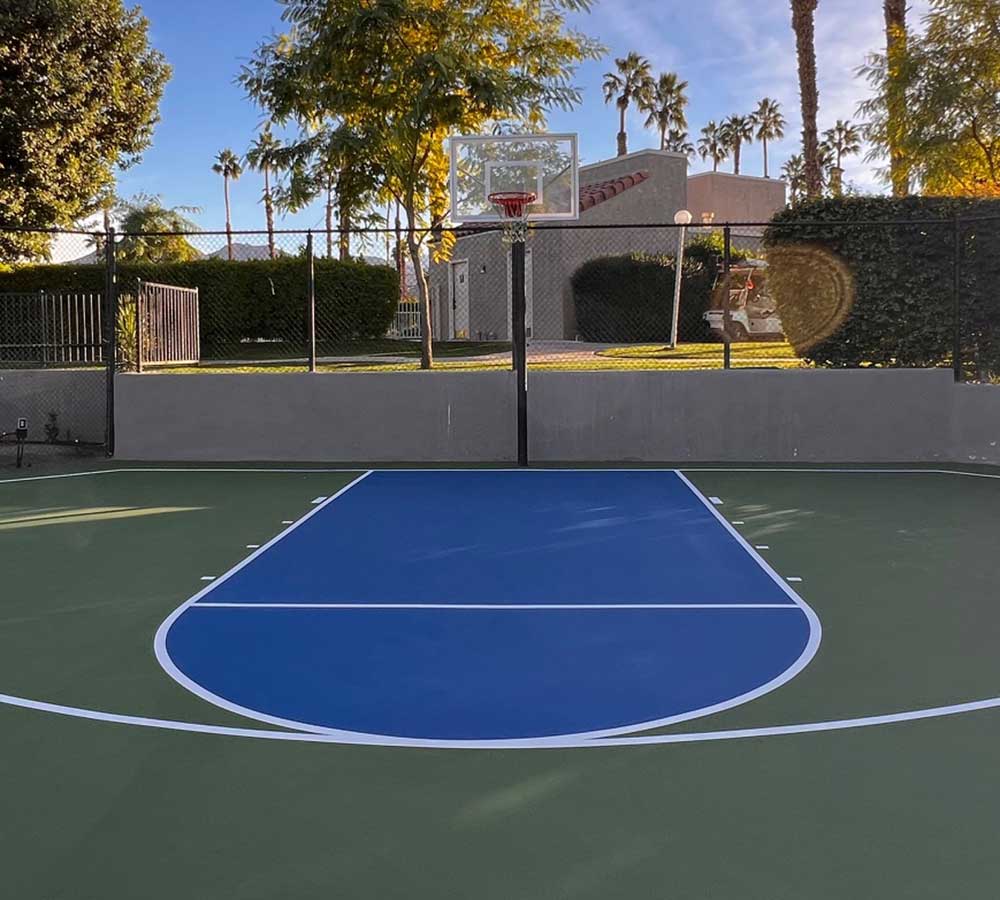 photo shows a beautiful blue half basketball court in an HOA complex.