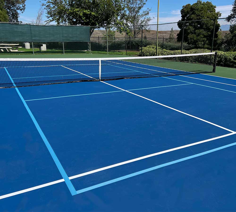 photo shows a multi-sport game court with tennis and pickleball striping.