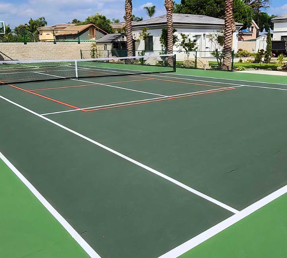 photo shows a dark green tennis court with pickleball striping in orange.