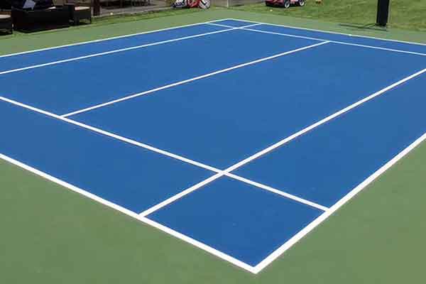 photo shows a blue badminton court with green surround and white striping.-1