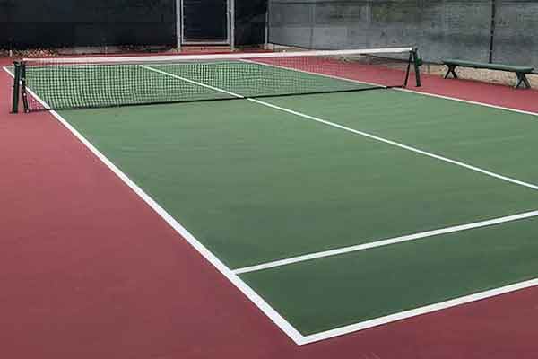photo shows a green paddle tennis court, red surround, and white striping.-1