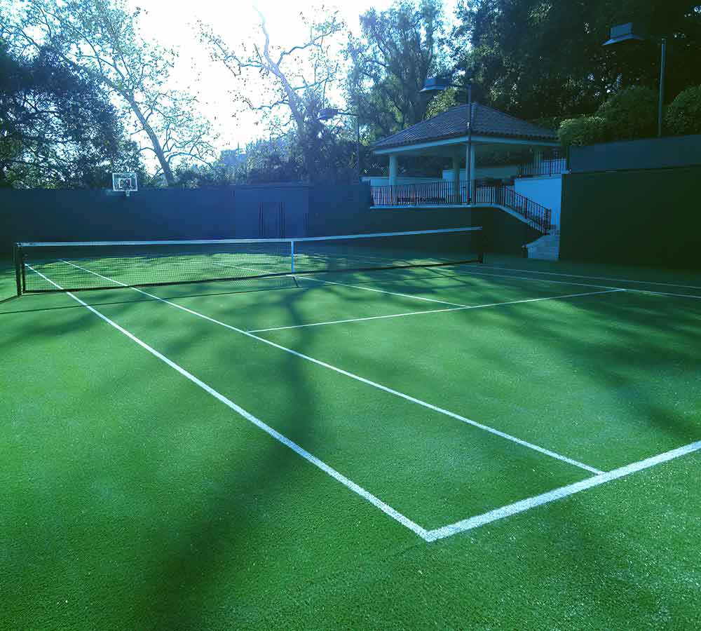 photo shows a gorgeous tennis court built with a artificial turf surround.