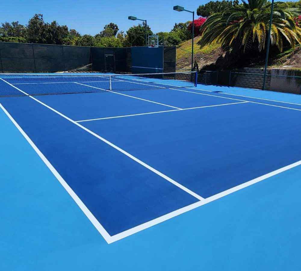 photo shows a gorgeous royal blue tennis court with a sky blue surround.